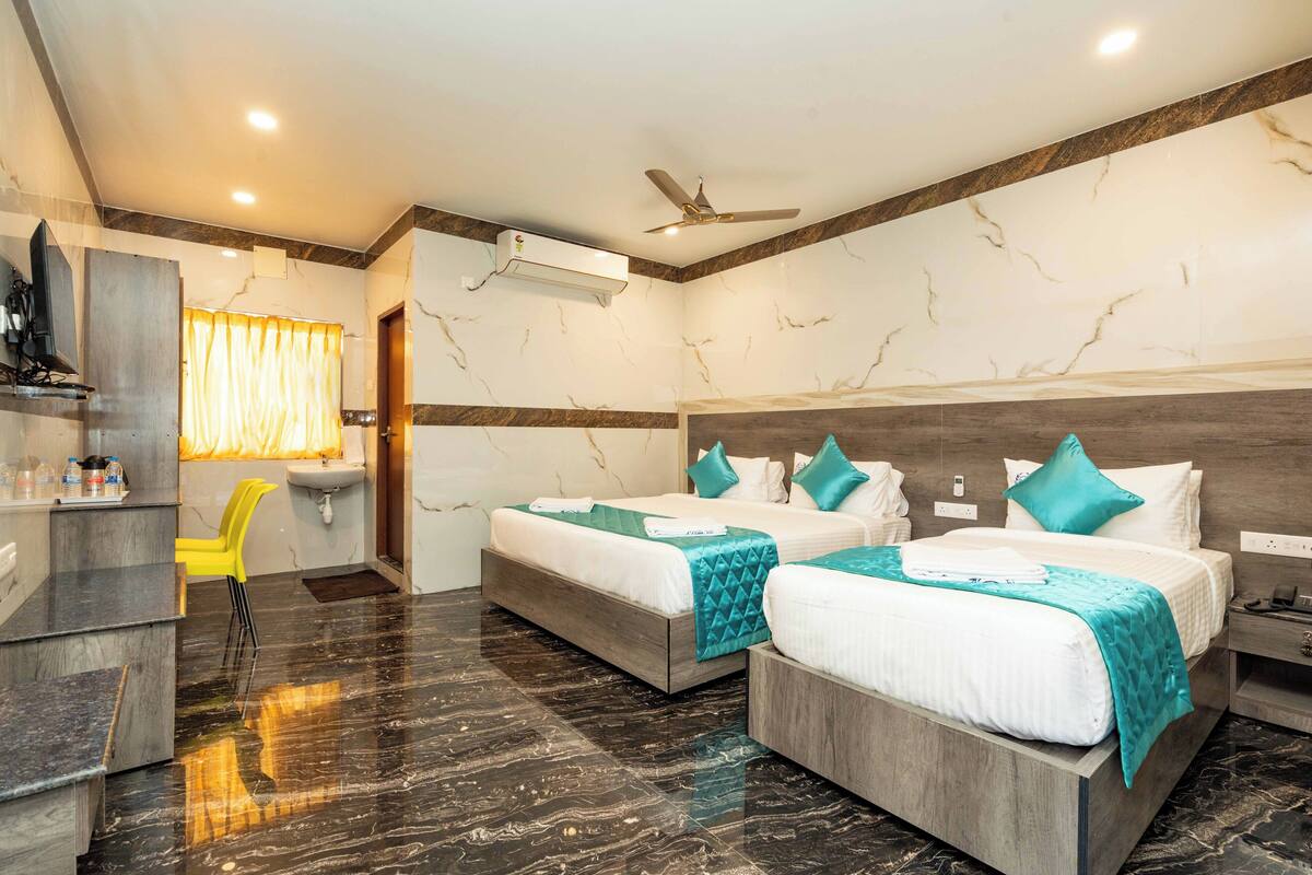 A hotel room with two beds, a desk, a chair, and a vanity.