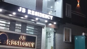 Un edificio con un cartello che indica “JB RESIDENCY” e una scala che conduce all'ingresso.