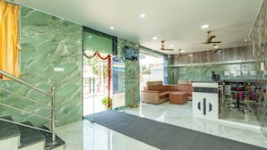 Un'hall dell'albergo con una scalinata in marmo, una reception, un'area salotto e ventilatori a soffitto.