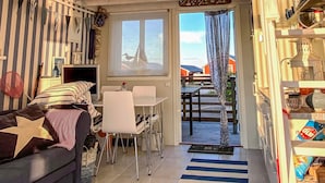 Ein gemütliches Wohnzimmer mit einer gestreiften Couch, einem Essbereich mit Tisch und Stühlen und einem Blick ins Freie durch ein Fenster.