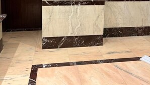 Zona de recepción de un hotel con pared de mármol, logotipo dorado y panel de control.