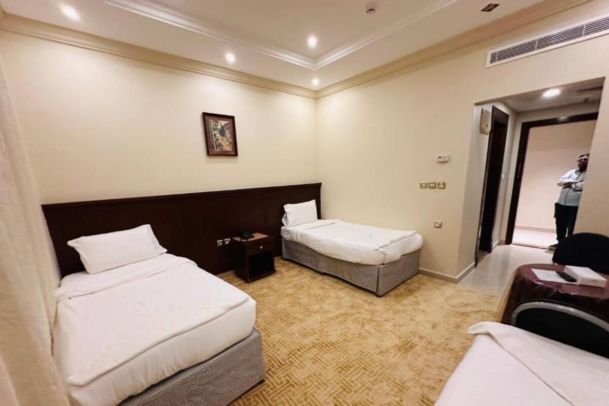 Une chambre d’hôtel avec deux lits, un petit bureau, une chaise et une porte donnant sur une salle de bain.