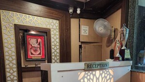 A reception desk with a 'Valley Pride' sign, a framed artwork, a trophy, and a 'Check Out Time' sign.