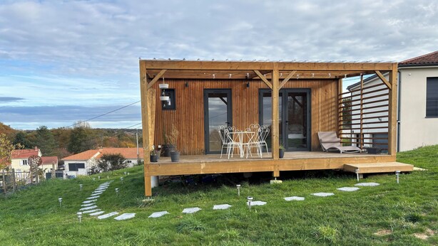 A wooden deck with outdoor furniture, a glass door entrance, and a view of the landscape. - Tiny House with Jacuzzi on terrace, view of Limoges. (Feytiat)
