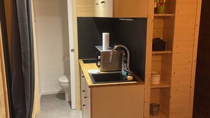 A compact kitchen with wooden cabinets, a sink, and a small countertop. - Tiny House with Jacuzzi on terrace, view of Limoges. (Feytiat)