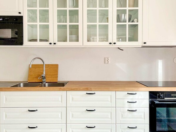 A kitchen with white cabinets, a wooden countertop, a stainless steel sink, and a black oven. - 4 Star Holiday Home in Sollentuna (Sollentuna)
