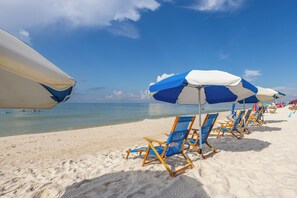 A beach with rows of blue and white beach chairs and umbrellas.