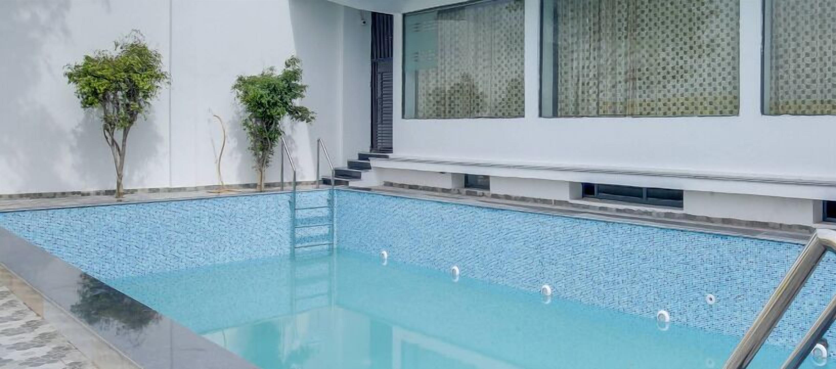 A rectangular swimming pool with a clear blue water surface, surrounded by a white wall with a window.