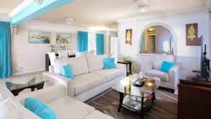 Un salon comprenant un canapé, des fauteuils, une table basse et un coin repas avec une table et des chaises.