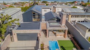 A modern residential building with a rooftop pool, solar panels, and a view of the ocean.