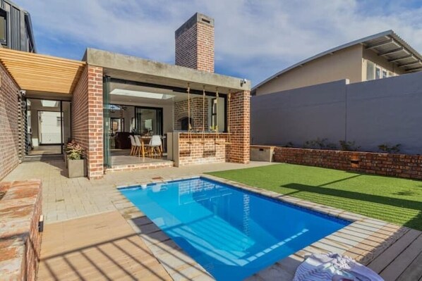 A modern house with a swimming pool, a patio, and a brick exterior.