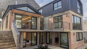 Et moderne hus med to etager, en balkon, store vinduer og en trappe, der fører op til øverste etage.