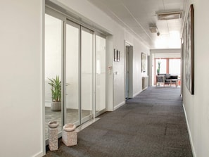 A corridor with sliding glass doors, a potted plant, and a small seating area with a table and chairs. - 5 Star Holiday Home in Thyboron (Thyborøn)