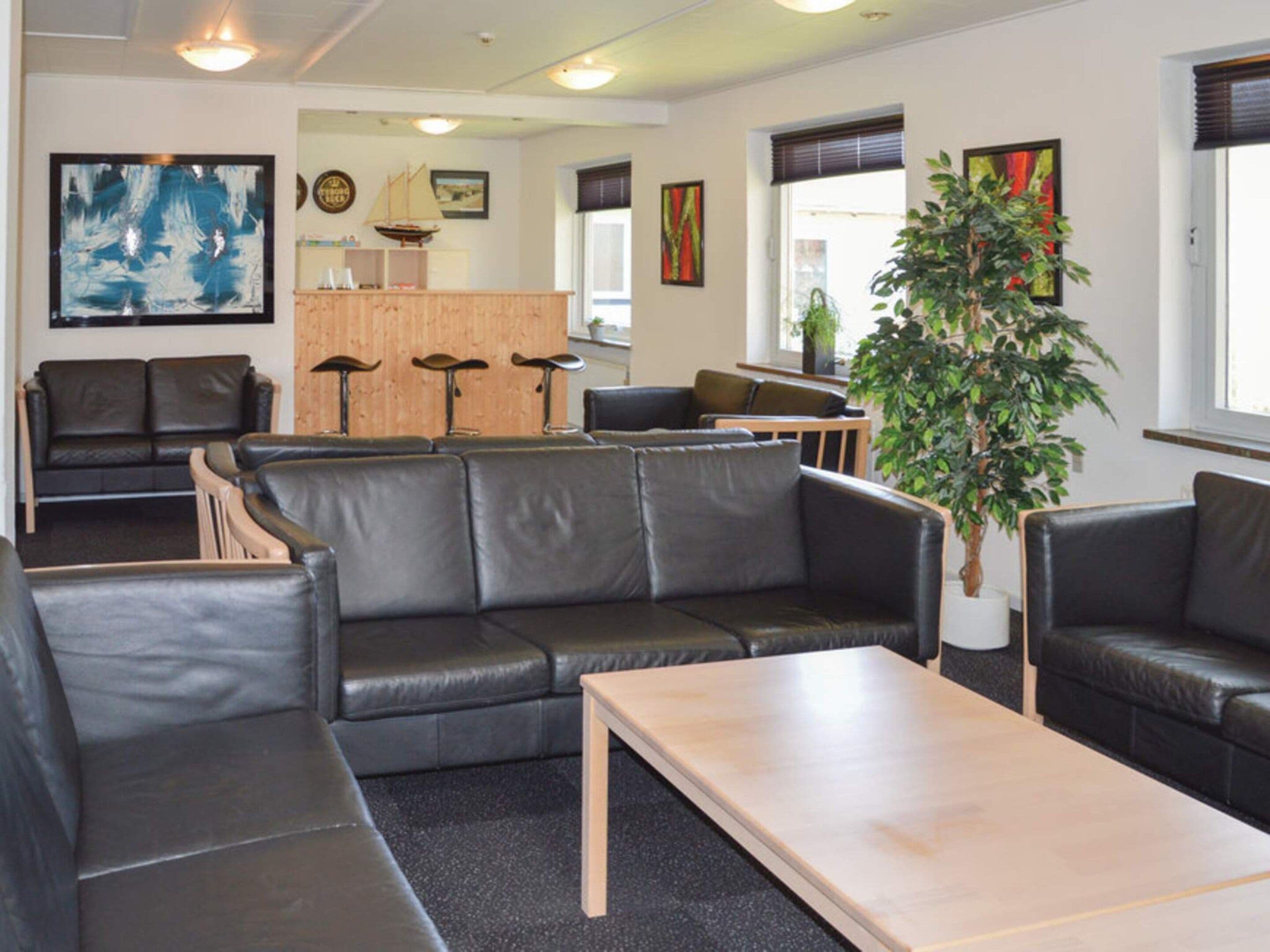 A modern lounge area with leather sofas, a wooden coffee table, and a reception desk with bar stools.