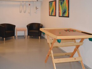 Een kamer met een pooltafel, twee stoelen en twee abstracte schilderijen aan de muur.