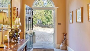 A hallway with a wooden bench, a door leading outside, and a vase with an umbrella.