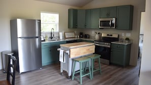 A modern kitchen with green cabinets, stainless steel appliances, and a wooden island with stools. - Charming 1-bedroom farmhouse in marvelous Seneca with WiFi, AC (Seneca)
