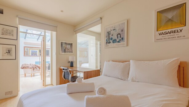 Een hotelkamer met een groot bed, een bureau en een stoel. Er hangen ingelijste kunstwerken aan de muren en een raam met uitzicht.