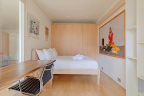 Ein modernes Hotelzimmer mit Bett, einem Holztisch, einem Stuhl und einem Bild an der Wand.