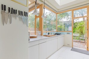 Una cocina moderna con un amplio ventanal, un organizador para cuchillos y un lavamanos.