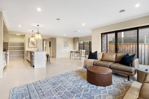 A spacious living area with a sofa, ottoman, and a patterned rug.