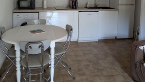 Eine kompakte Küche mit weißen Schränken, einer Mikrowelle, einer Kaffeemaschine und einem Spülbecken.