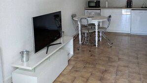 Eine kompakte Küche mit Mikrowelle, Kaffeemaschine und einer Essecke mit Tisch und Stühlen.