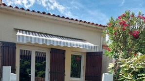 Eine überdachte Terrasse mit Tisch und Stühlen, eine Holzterrasse und ein Gartenbereich.