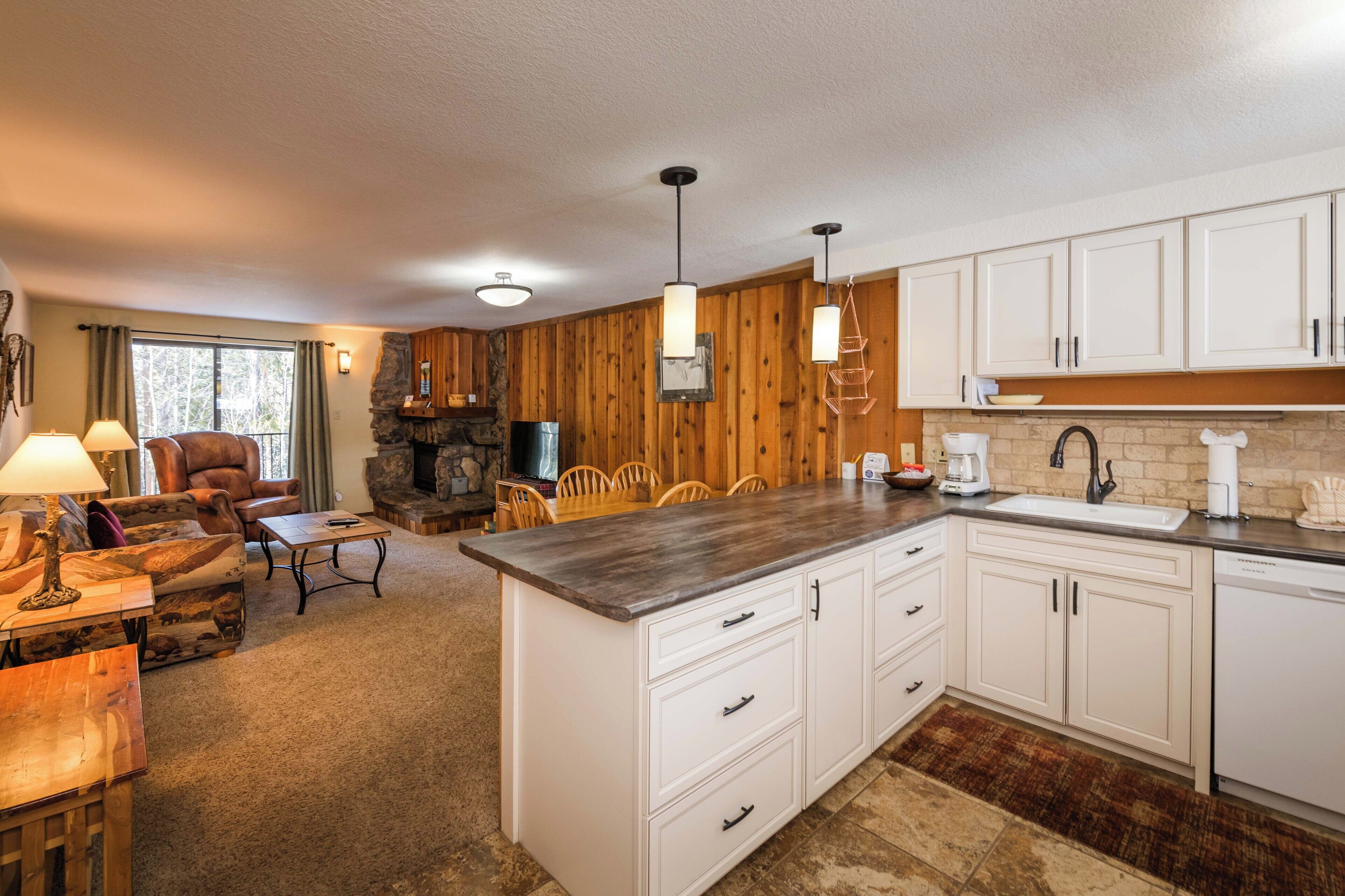 A kitchen with white cabinets, a wooden island, and a stone fireplace.