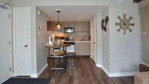 A compact kitchen with a dining area, a television, and a decorative wall piece. - Ski In Ski Out Cozy Studio (Blue Mountain)