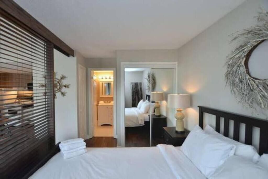 Una habitación de hotel con cama, mesita de noche, lámpara y espejo.