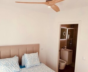 A bedroom with a bed, a ceiling fan, and a bathroom visible through an open door. - Lagos Town Center Apartment Near Shops, Beaches (Lagos)