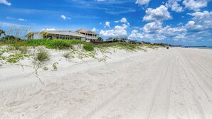 A sandy beach with beachfront houses and a pier in the background. - Peace of Heaven Three Bedroom Oceanfront Home in Long Bay Estates (Myrtle Beach)