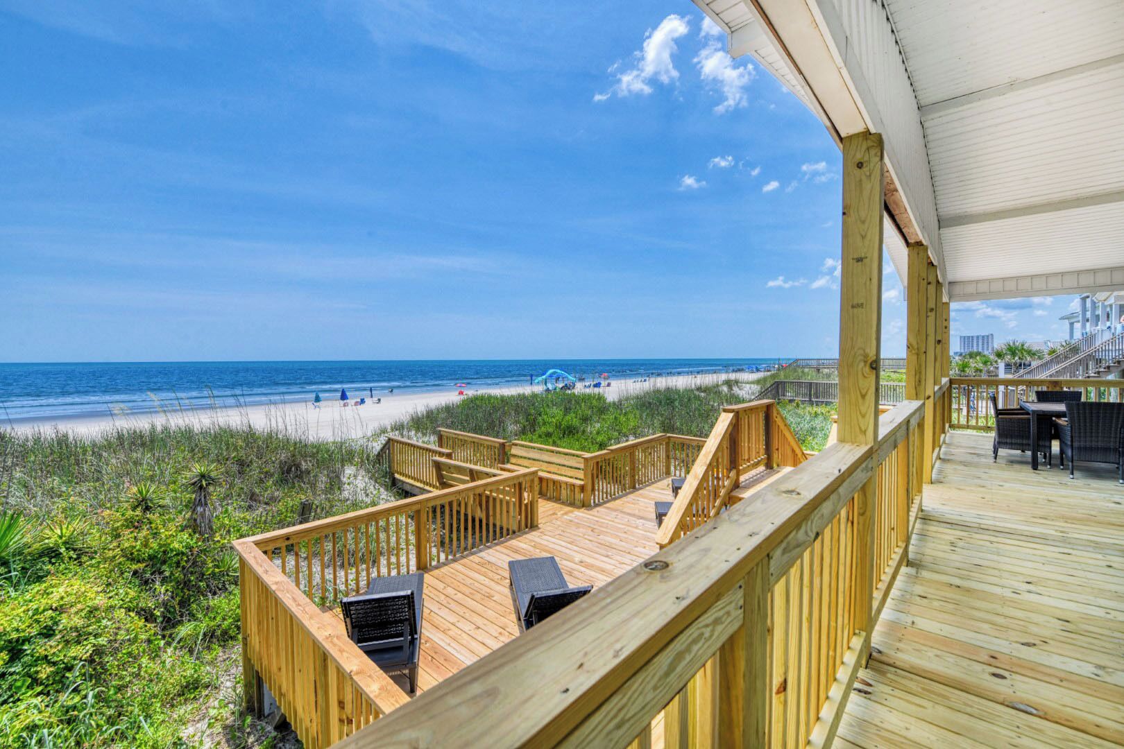 Eine Holzterrasse mit Sitzgelegenheiten mit Blick auf einen Strand.