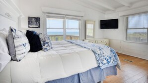 A bedroom with a large bed, a TV, and a view of the ocean. - Peace of Heaven Three Bedroom Oceanfront Home in Long Bay Estates (Myrtle Beach)