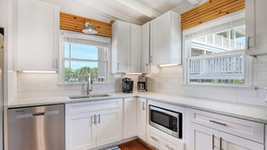 A modern kitchen with white cabinets, stainless steel appliances, and wooden ceiling beams. - Peace of Heaven Three Bedroom Oceanfront Home in Long Bay Estates (Myrtle Beach)