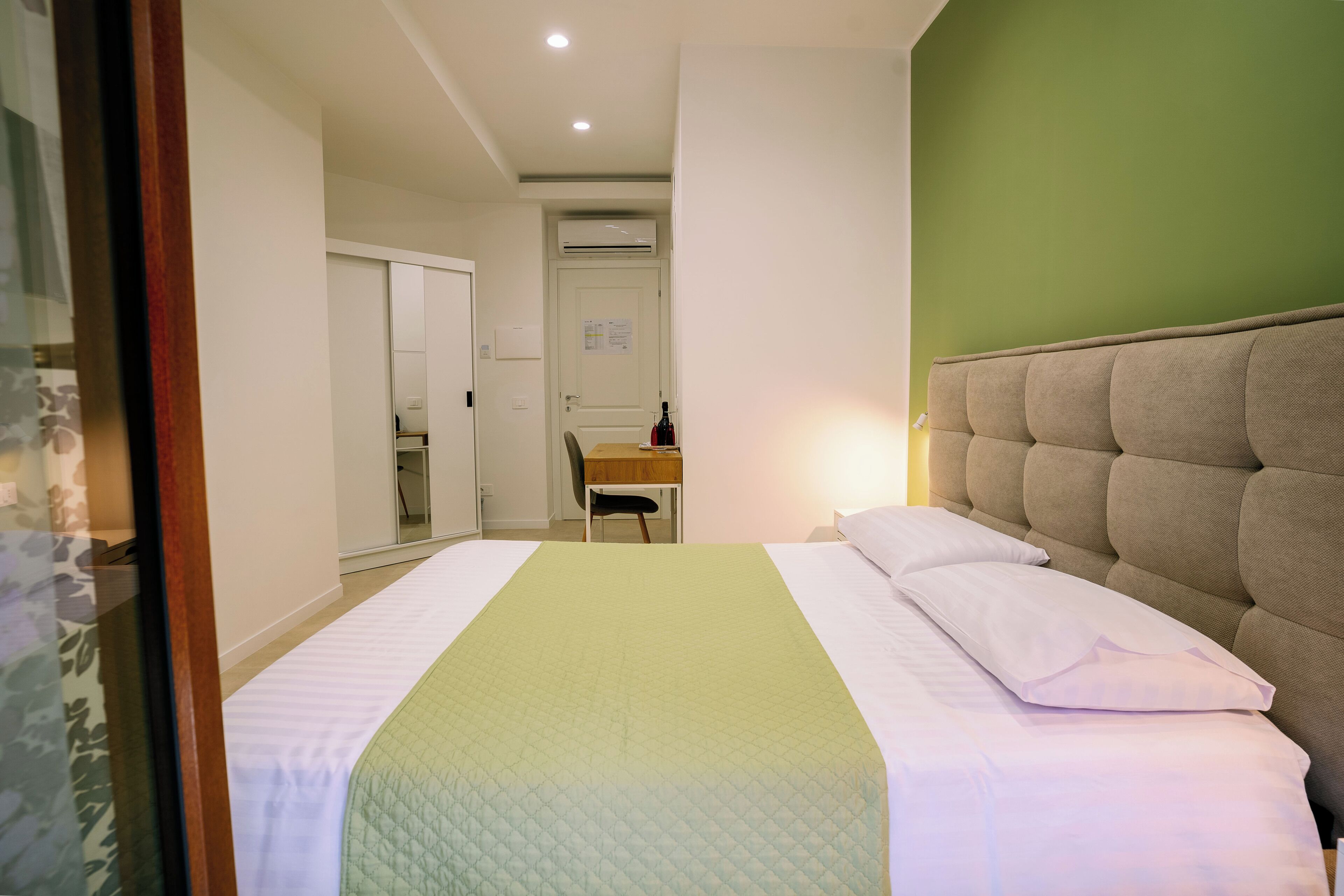 Quarto de hotel com cama, escrivaninha e cadeira.