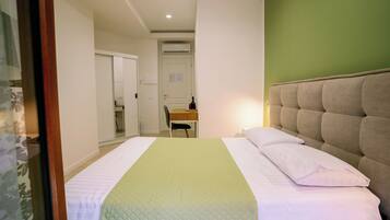 Quarto de hotel com cama, escrivaninha e cadeira.
