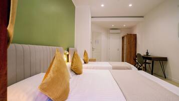 A hotel room with two beds, a desk, and a wardrobe.