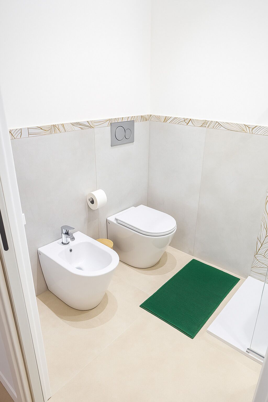Un baño pequeño y moderno con un bidé, un inodoro y un tapete verde en el suelo.