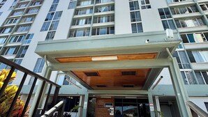 A multi-story hotel with a covered entrance, a staircase leading to the entrance, and a clear sky.