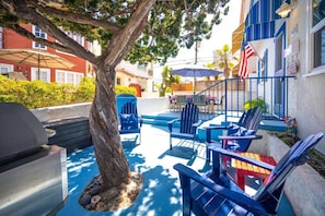 Un área junto a la piscina con sillas tipo Adirondack, una parrilla y una bandera estadounidense.
