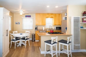 A compact kitchen with a dining area, wooden cabinets, a gas stove, and a microwave.