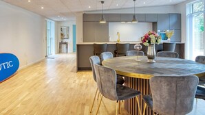 A modern dining area with a round table, grey upholstered chairs, and a vase of flowers. - 5 Star Holiday Home in Sjaellands Odde (Sjællands Odde)