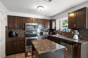 A modern kitchen with dark wood cabinets, stainless steel appliances, and a granite countertop.