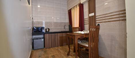 A compact kitchen with a refrigerator, a sink, and a dining table with chairs.