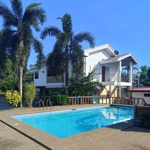 A two-story building with a swimming pool, surrounded by palm trees and other greenery. - Seaheart Guest House Panglao (Panglao)