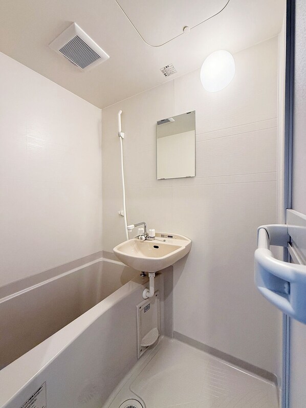 Un baño con bañera, lavabo, espejo y ducha.