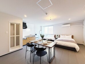 Habitación de hotel compacta con kitchenette, comedor y cama.