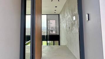 A modern interior with a wooden ceiling, a concrete floor, and a view of a balcony with a metal railing.